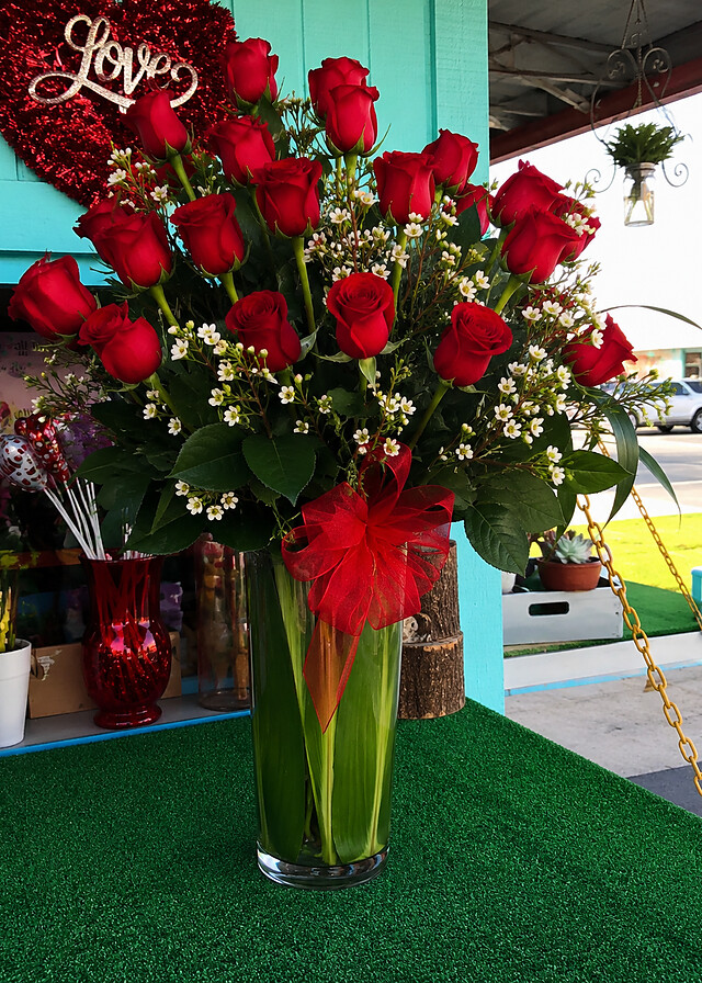 Two dozen red roses arrangement at the teal Blossoms Flower Shop storefront on Ulric St